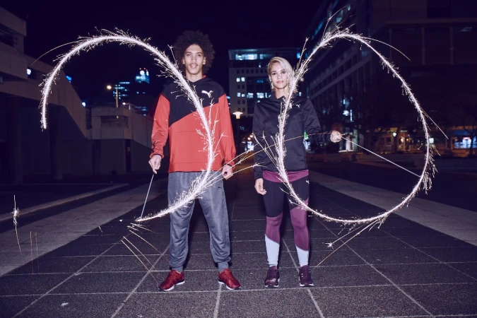 Two models holding sparklers creating glowing light arcs outdoors at night, photographed by Jon Johnson.