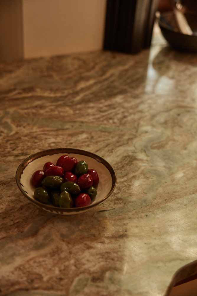 Bowl of red and green olives sits on a patterned table in a restaurant, creating an appetizing still life for a food-themed visual.