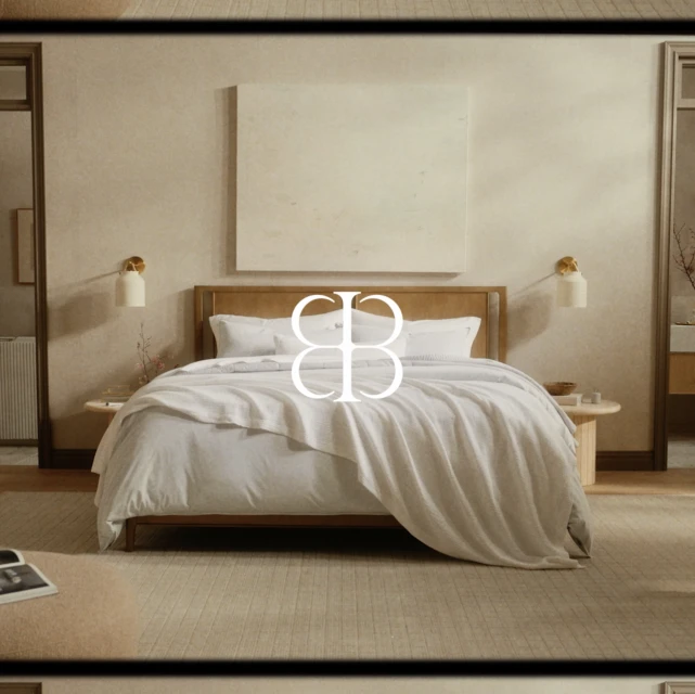 Interior of a bedroom with a king-size bed, wooden headboard, a large square painting, and two small round side tables.