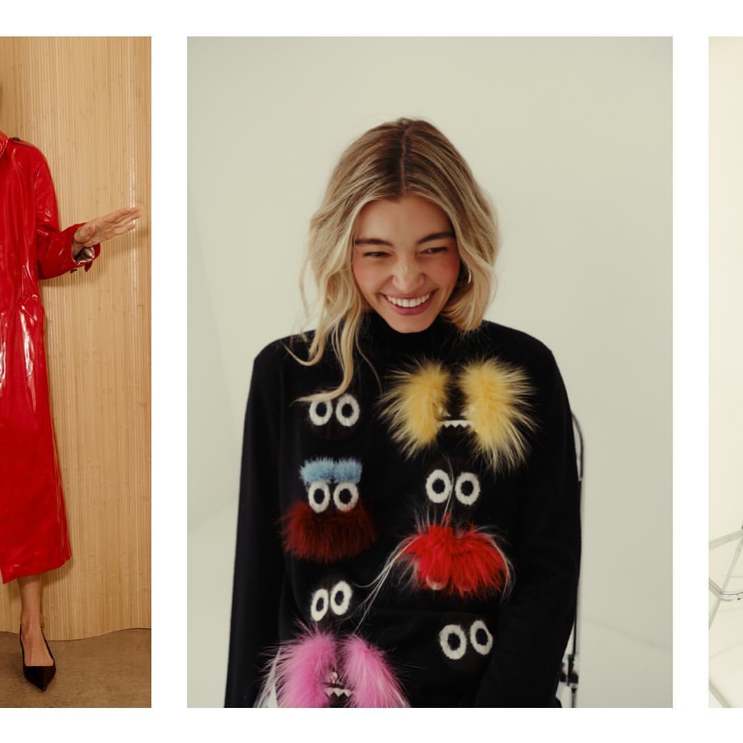 A smiling woman wears a black sweater with colorful fuzzy monster-eye appliqués in a bright studio setting. Fashionable and playful design.