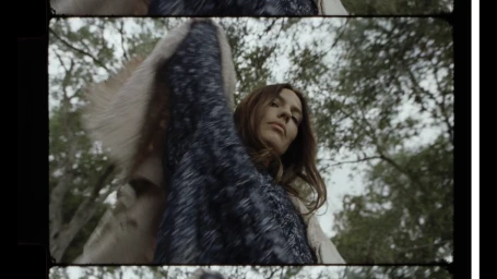 Low angle portrait of a woman outdoors looking down with trees and sky in the background