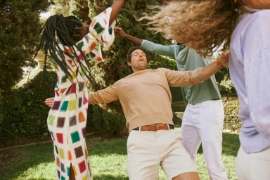 Group of diverse friends dancing outdoors in a sunlit garden, captured by photographer Kate Moore.