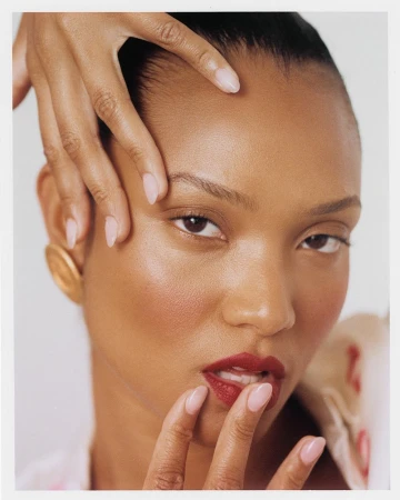 Close-up portrait of a woman with deep red lipstick and manicured nails framing her face, photographed in Los Angeles.