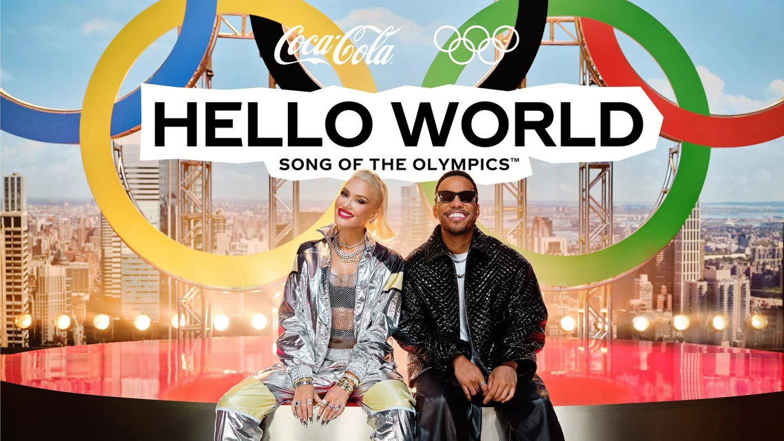 Coca-Cola Olympic promotional image of Gwen Stefani and Taio Cruz sitting in front of a backdrop of a city skyline and Olympic rings.