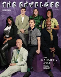 Group portrait of seven smiling actors posed against a textured purple backdrop for magazine cover.