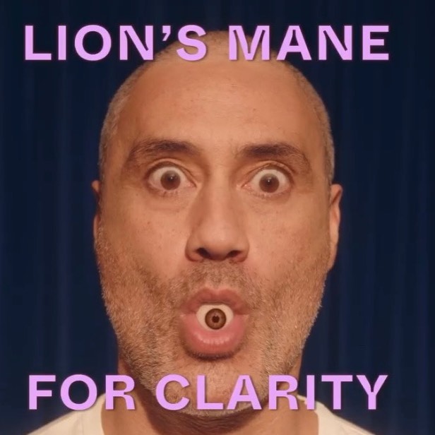 Close-up of a bald adult male with an eye in his mouth, set against a dark blue curtain backdrop with text overlaying the image.