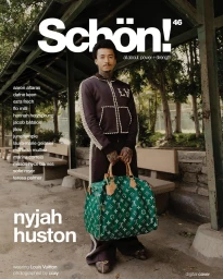 Skater Nyjah Huston holding a large green monogram duffel bag while standing on an outdoor wooden pavilion.