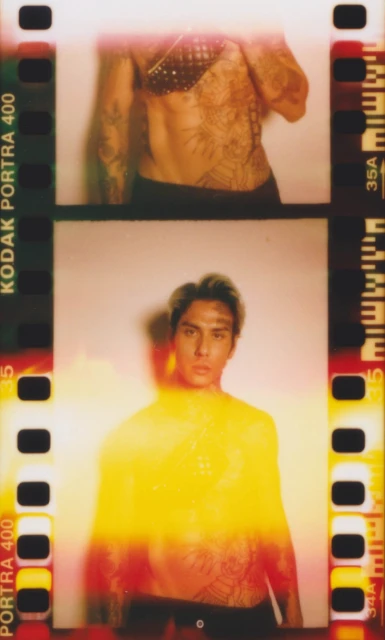 Analog film strip image of a tattooed adult male with yellow light. Top frame shows torso, bottom frame shows torso and head.