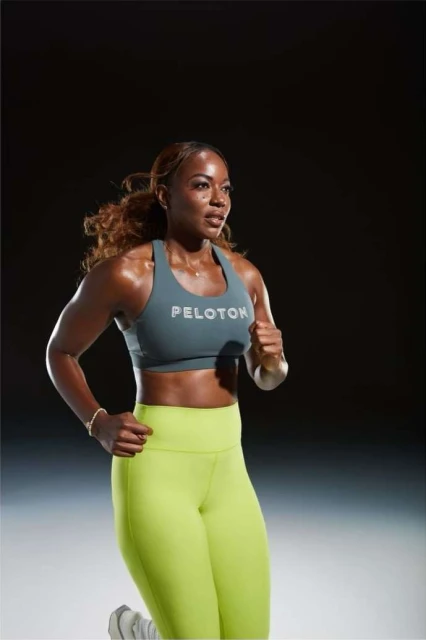 Athletic woman running in fitness apparel. The model is wearing a Peloton sports bra and leggings, showcasing a workout scene.