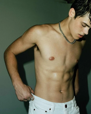 Shirtless young man wearing a silver chain necklace and white jeans in Los Angeles by Camraface