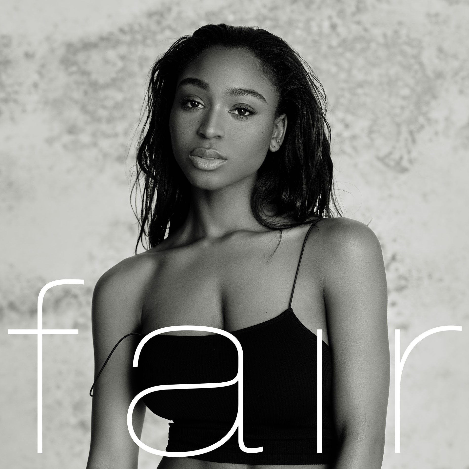Monochrome portrait of a young African-descent woman with dark hair wearing a black top, set against a grey, textured background.
