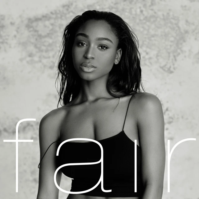 Monochrome portrait of a young African-descent woman with dark hair wearing a black top, set against a grey, textured background.