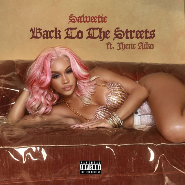 Saweetie laying on a couch with gold jewelry and a pink wig, album cover for "Back To The Streets" ft. Jhene Aiko.