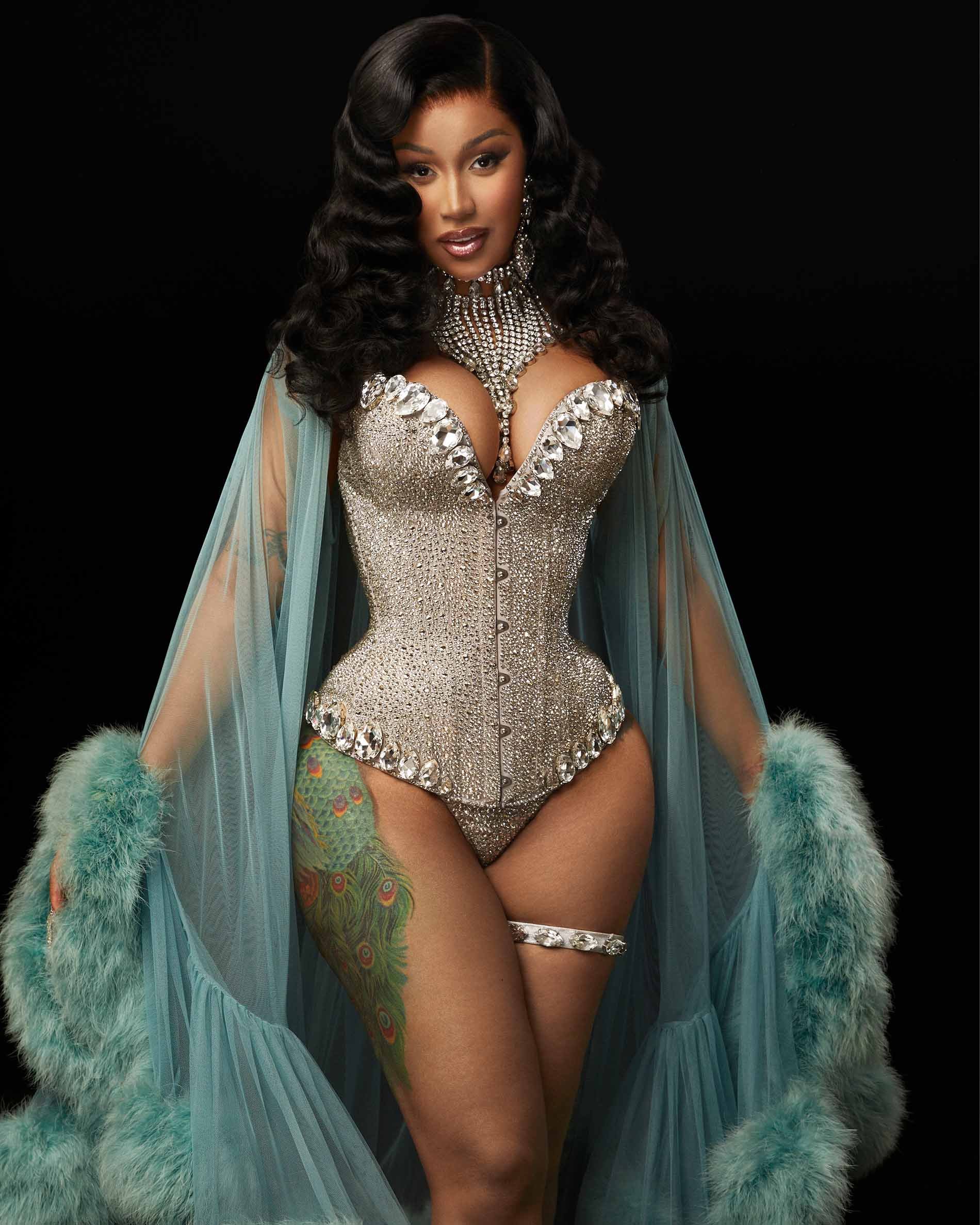 Adult female in a studio shot wearing a sparkly rhinestone-studded corset, necklace and matching garter, teal boa and tulle wrap.