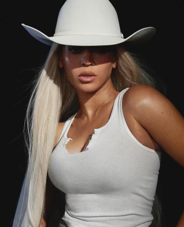 Beyonce wearing a white cowboy hat and white ribbed tank top against a dark background in a portrait photograph by Blair Caldwell