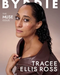 Close-up portrait of Tracee Ellis Ross wearing a dark brown leather jacket against a soft gradient background.