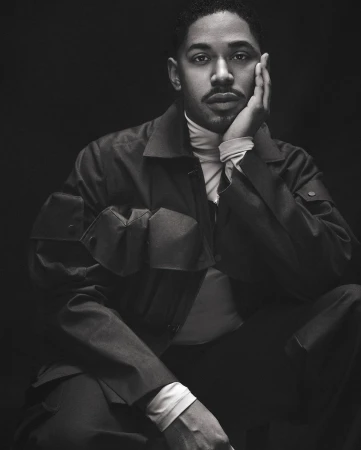 Portrait of a Black man with a mustache wearing a turtleneck and utility jacket, photographed by Isaac Anthony in monochrome.