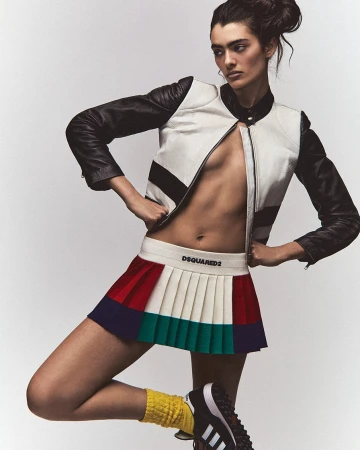 Model wearing a white and black leather jacket and colorblocked pleated skirt against a white background