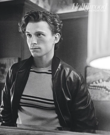 Monochrome portrait of adult male in striped sweater and bomber jacket, styled with curly hair and side glance. 'The Hollywood Reporter' logo.