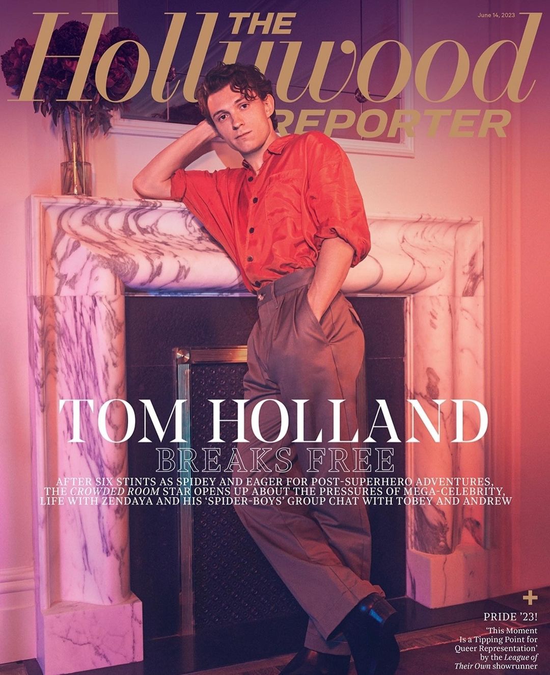 Magazine cover featuring Tom Holland in an unbuttoned red shirt and pleated slacks, leaning against a white marble fireplace mantel.
