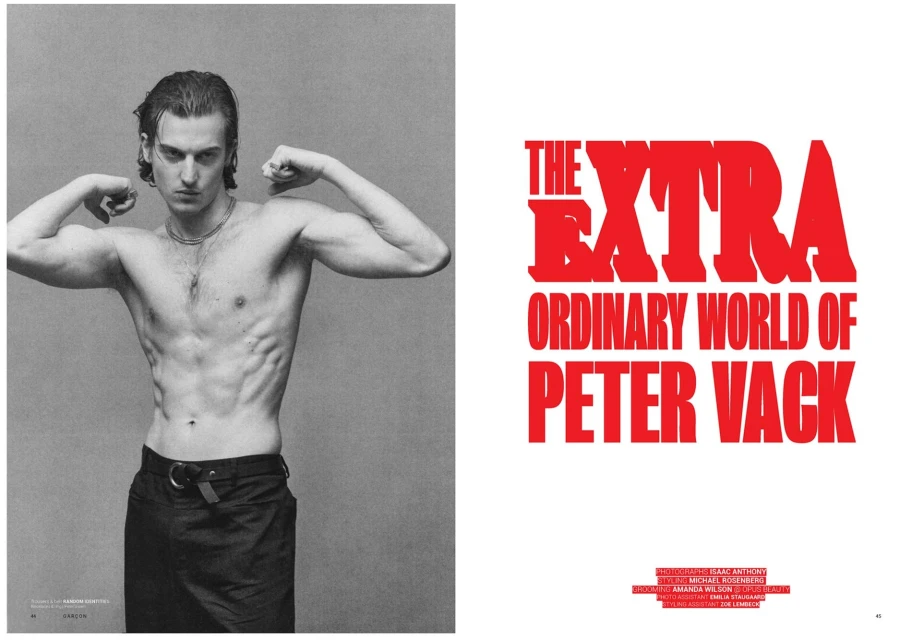 Editorial fashion shot of a shirtless adult male flexing his arms in a photo studio; the image has a magazine cover on the right side.