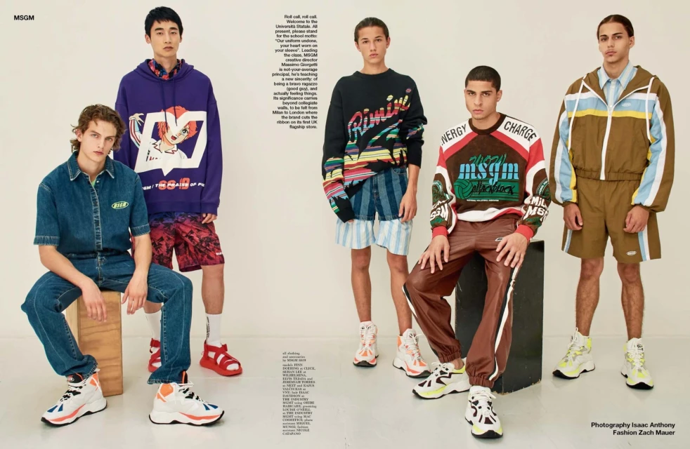 Five young adult male models pose in a photo studio, showcasing streetwear fashion with graphic hoodies, sweaters, shorts, pants, and sneakers.