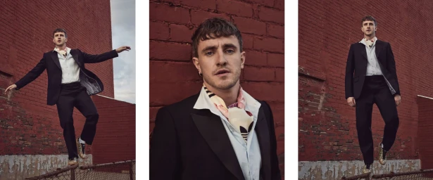 Triptych portrait of Paul Mescal wearing a black suit and patterned silk scarf against a weathered red brick wall