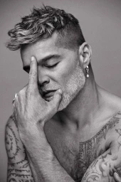 Monochrome portrait of a tattooed man with short textured hair touching his forehead with closed eyes, photographed by Isaac Anthony.