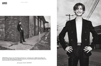 Black and white editorial layout by Isaac Anthony featuring a smiling man in a double-breasted blazer and another model leaning against a brick wall