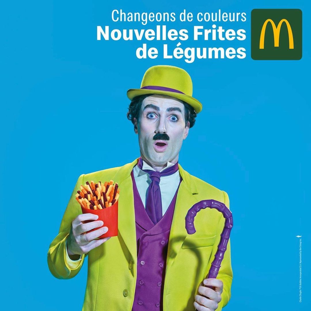 Person dressed as Charlie Chaplin holds french fries in a McDonald's advertisement against a blue background, promoting vegetable fries.