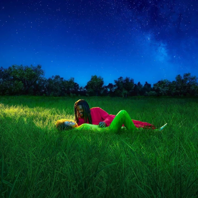 Two people, one adult man and one adult female, lying in a green grassy field underneath a starry night sky. Outdoor recreation.