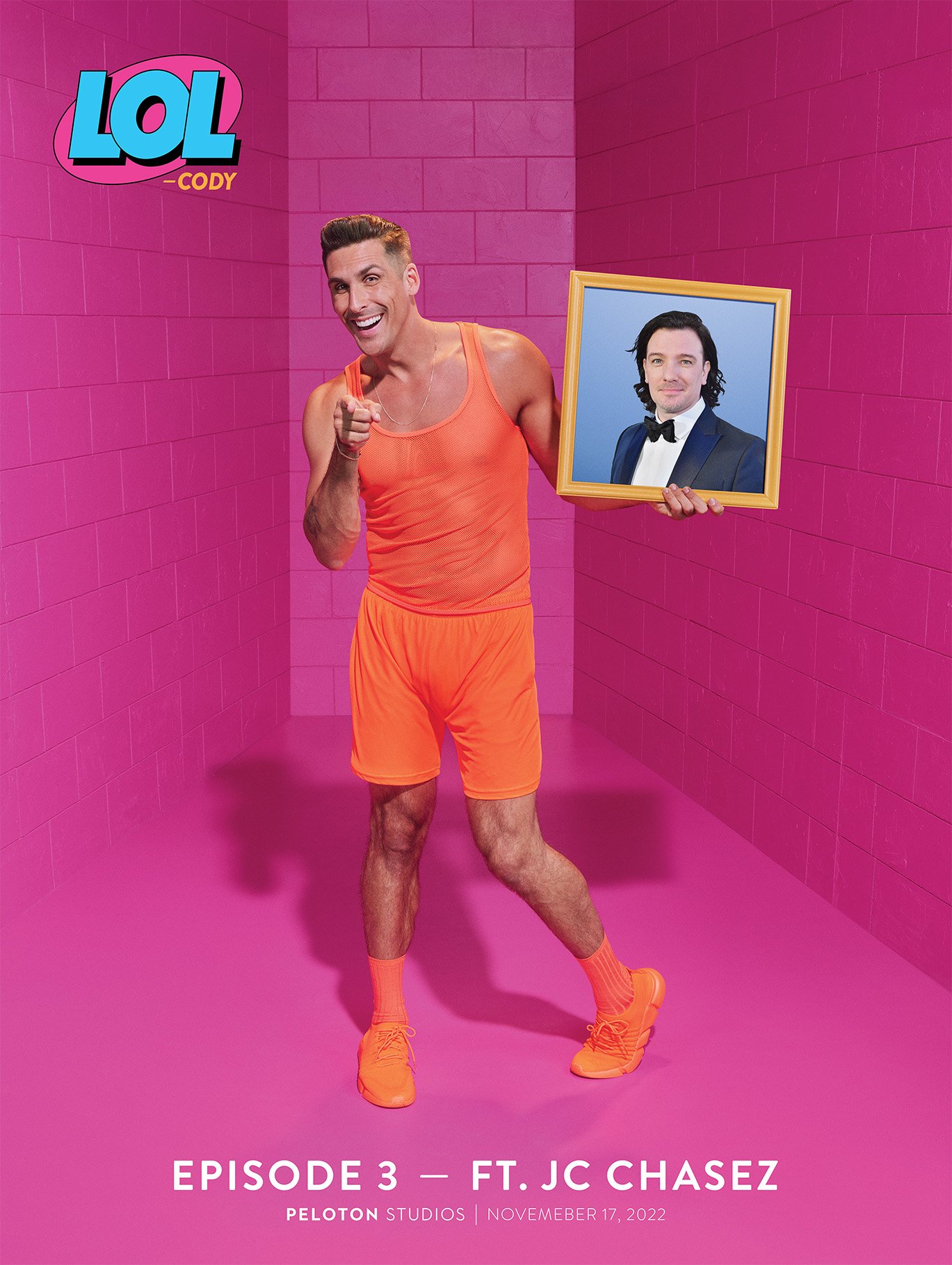 Man in orange athletic wear holds a framed portrait of JC Chasez against a pink brick wall in a promotional image for LOL Cody.