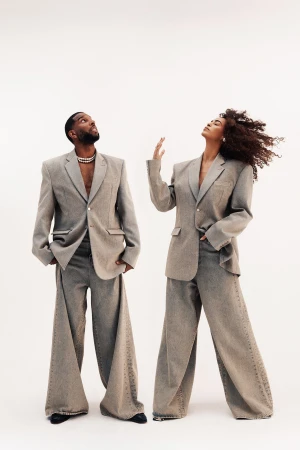 Two models wearing oversized grey blazers and matching wide-leg trousers posing against a plain white background
