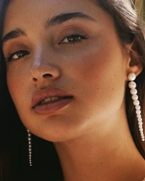 Close-up portrait of a woman wearing long gradient pearl earrings by photographer Martika Avalon.