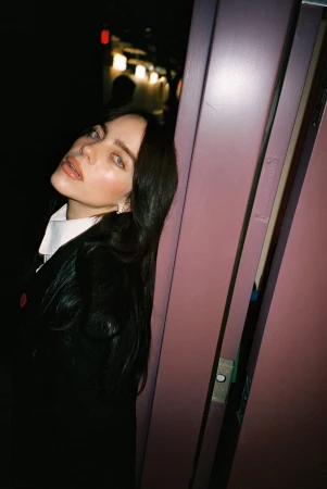 Portrait of a woman with dark hair leaning against a purple door frame, captured by photographer Zoe Donahoe.