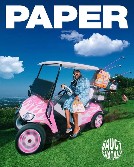 Saucy Santana poses in a pink golf cart on a grassy hill under a blue sky, promoting their album 'PAPER' with visible text.