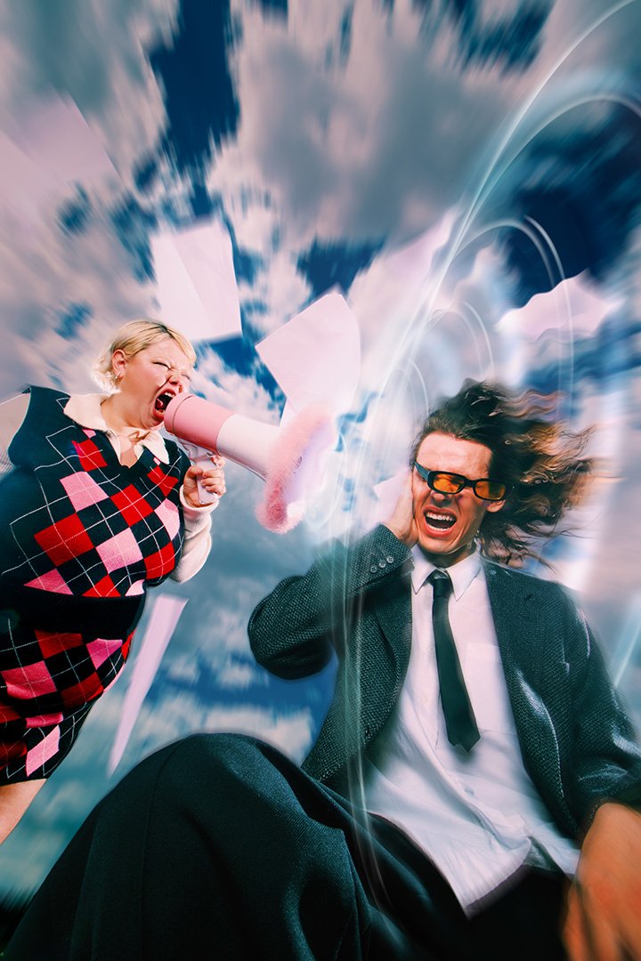 Woman yelling into a megaphone at a man covering his ears, with dynamic motion blur and scattered papers against a cloudy sky.
