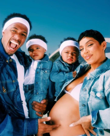 A family portrait featuring a man, woman, and two young children wearing matching denim jackets and white headbands, posing outdoors.