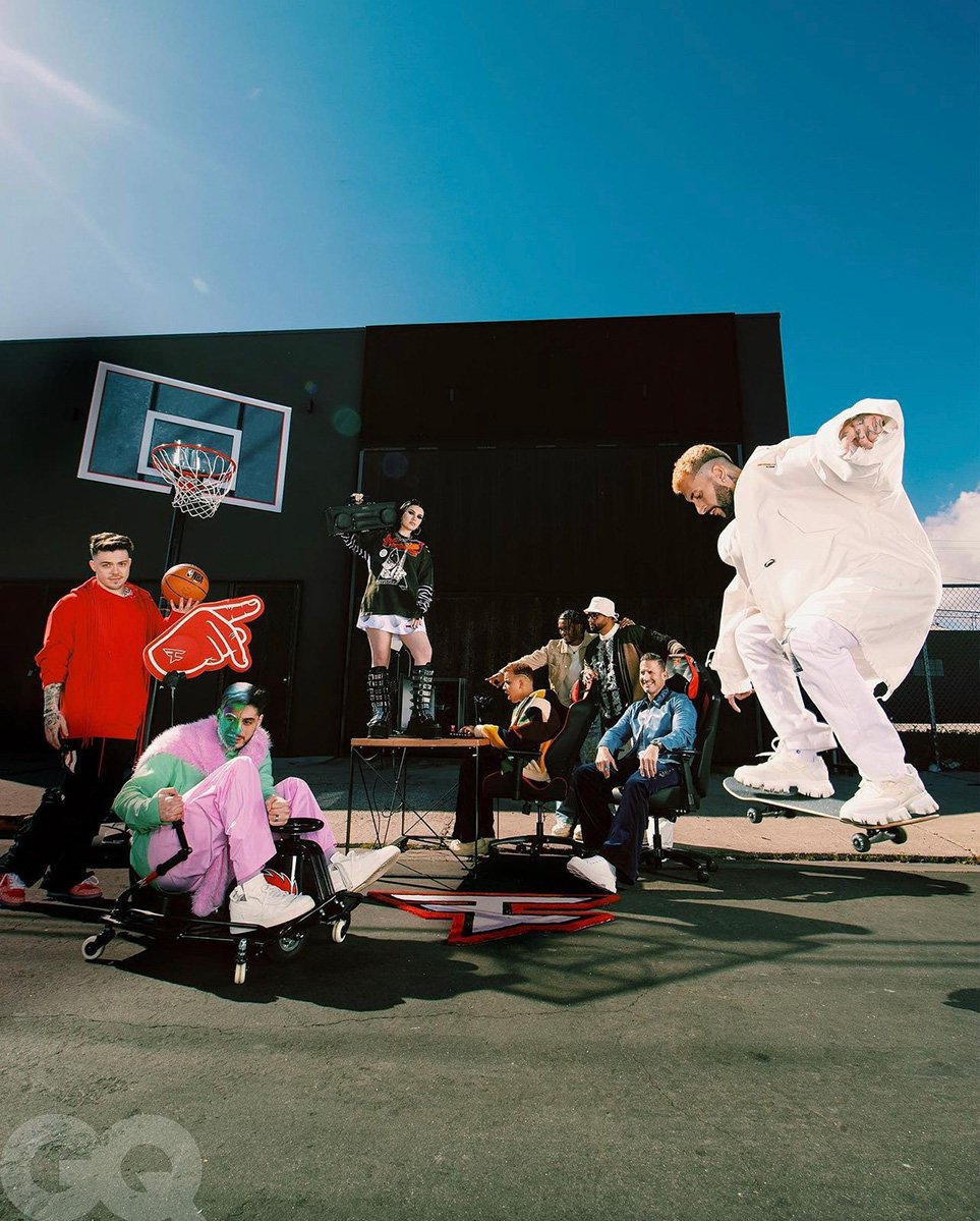 Group of people outdoors in stylish clothing posing in front of a dark building on a city street with a basketball hoop. 