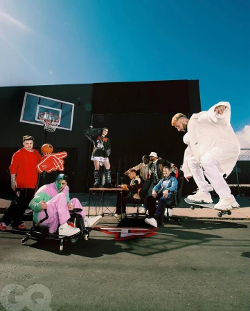 Group of people outdoors in stylish clothing posing in front of a dark building on a city street with a basketball hoop. 