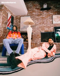 Two men posing in an interior room with a brick fireplace, photographed by Xavier Luggage.