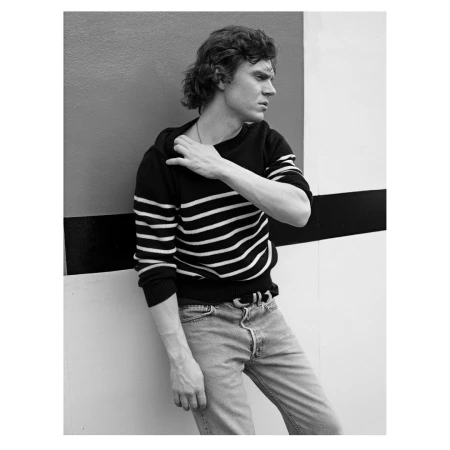 Portrait of a man in a striped sweater leaning against a geometric wall by Victoria Stevens