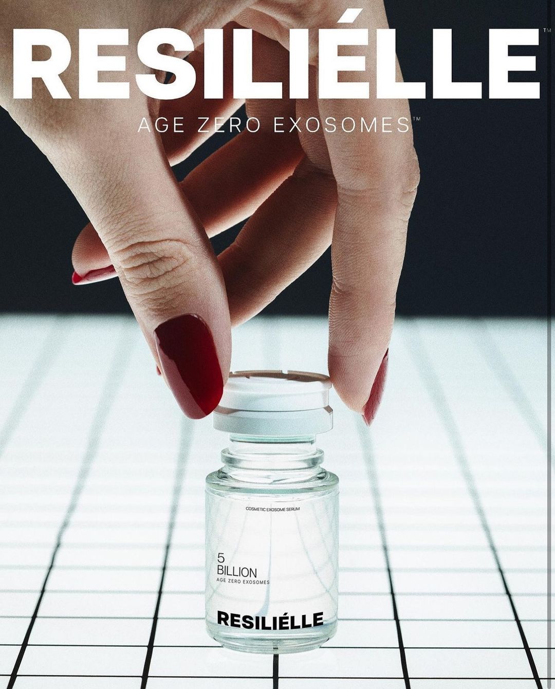 Hand holds a clear glass bottle of Resiliélle Age Zero Exosomes on a grid background with white and black colors, product advertisement.