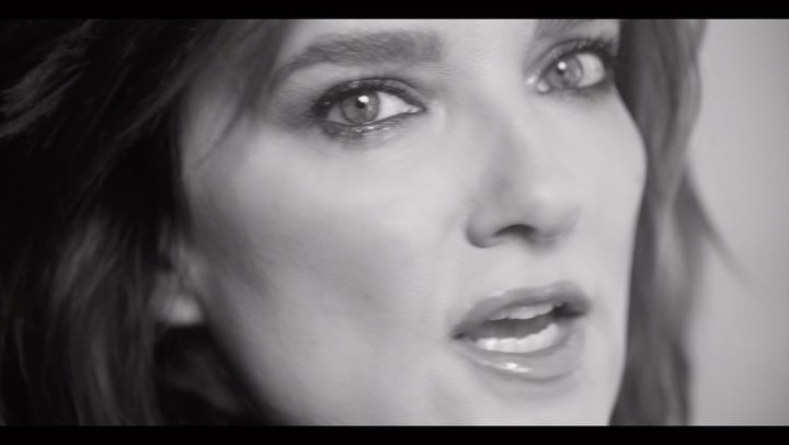 Close-up black and white portrait of a woman looking toward the camera with parted lips.