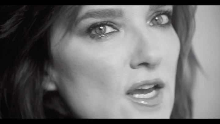 Close-up black and white portrait of a woman looking toward the camera with parted lips.