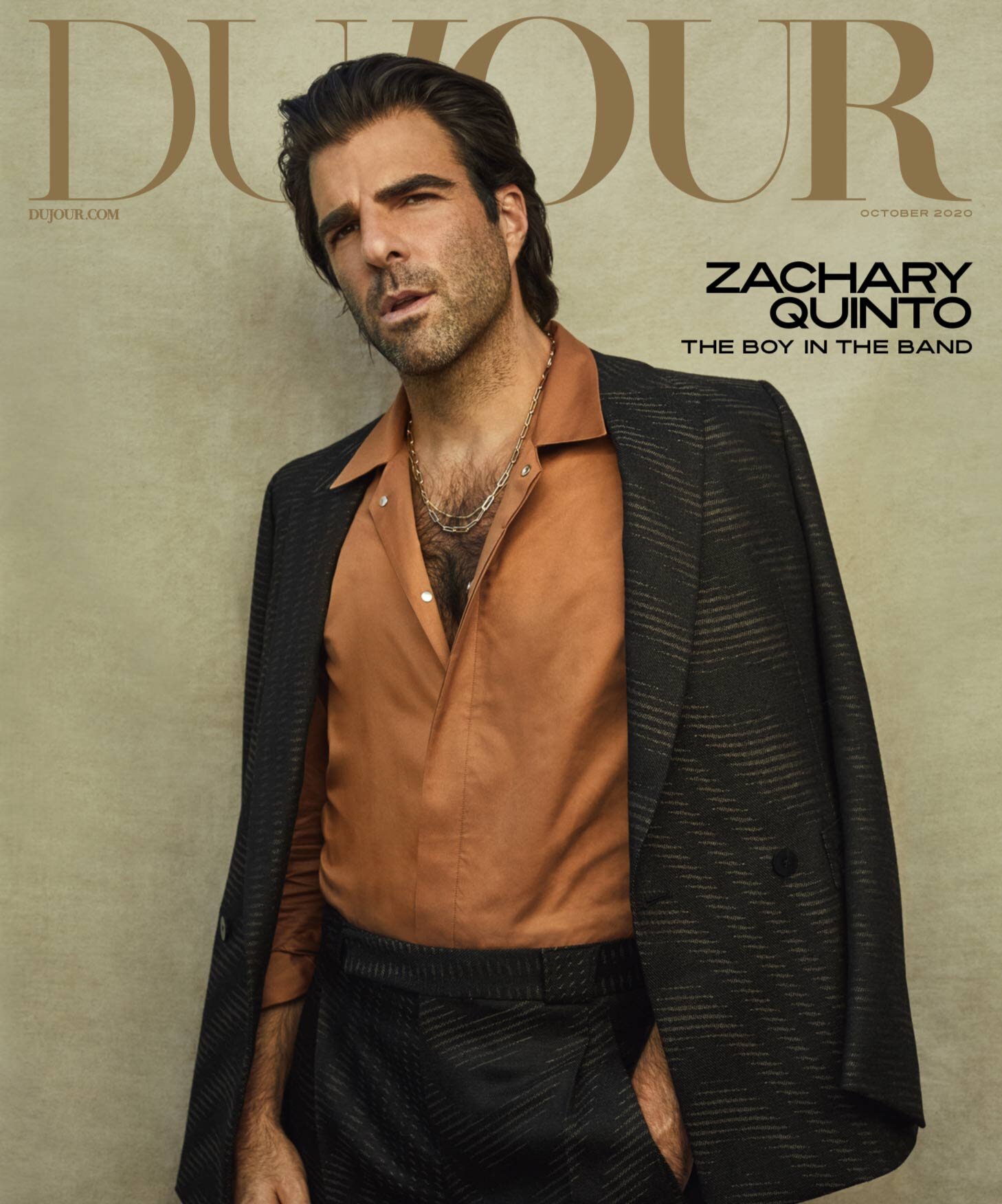 Magazine cover featuring Zachary Quinto in a brown shirt and patterned blazer, styled with a silver chain, against a neutral backdrop.