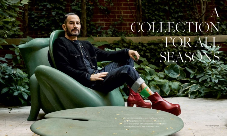 Marc Jacobs seated in a green sculpted armchair wearing a black jacket and red platform boots outdoors