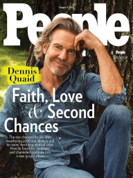 Actor Dennis Quaid smiling outdoors wearing a blue denim shirt against a textured tree trunk background