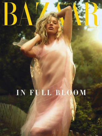 Model in a sheer pink tulle dress posing outdoors with blonde hair and sunlight filtering through trees