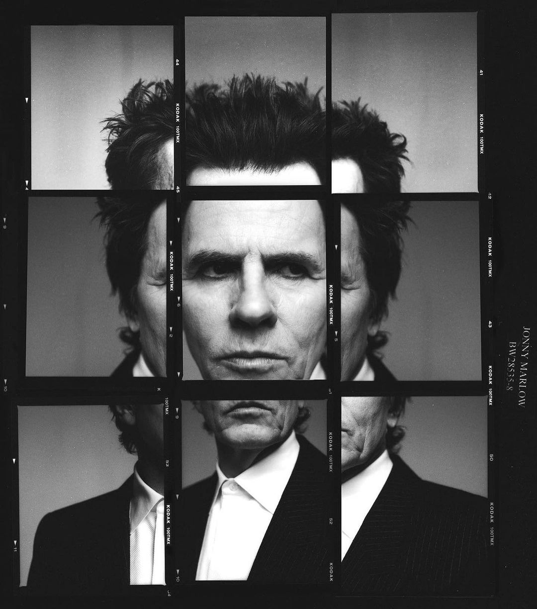 Black and white portrait of a man's face, repeated in a 3x3 grid with black borders. The man is wearing a dark suit and white collared shirt.